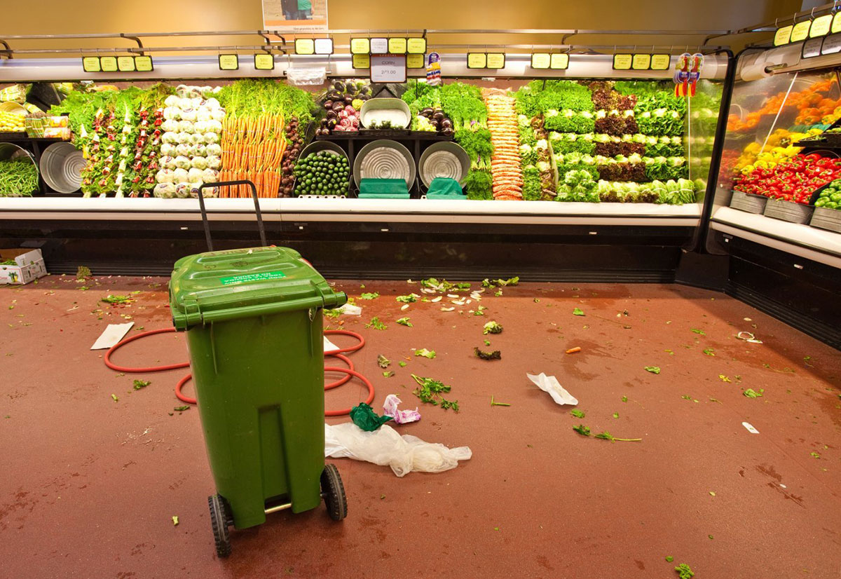 Produce section at the supermarket with vegetable scraps on the floor